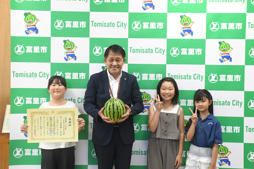 寄贈されたすいかを持つ五十嵐市長と、第一小学校生徒の皆さんの記念写真