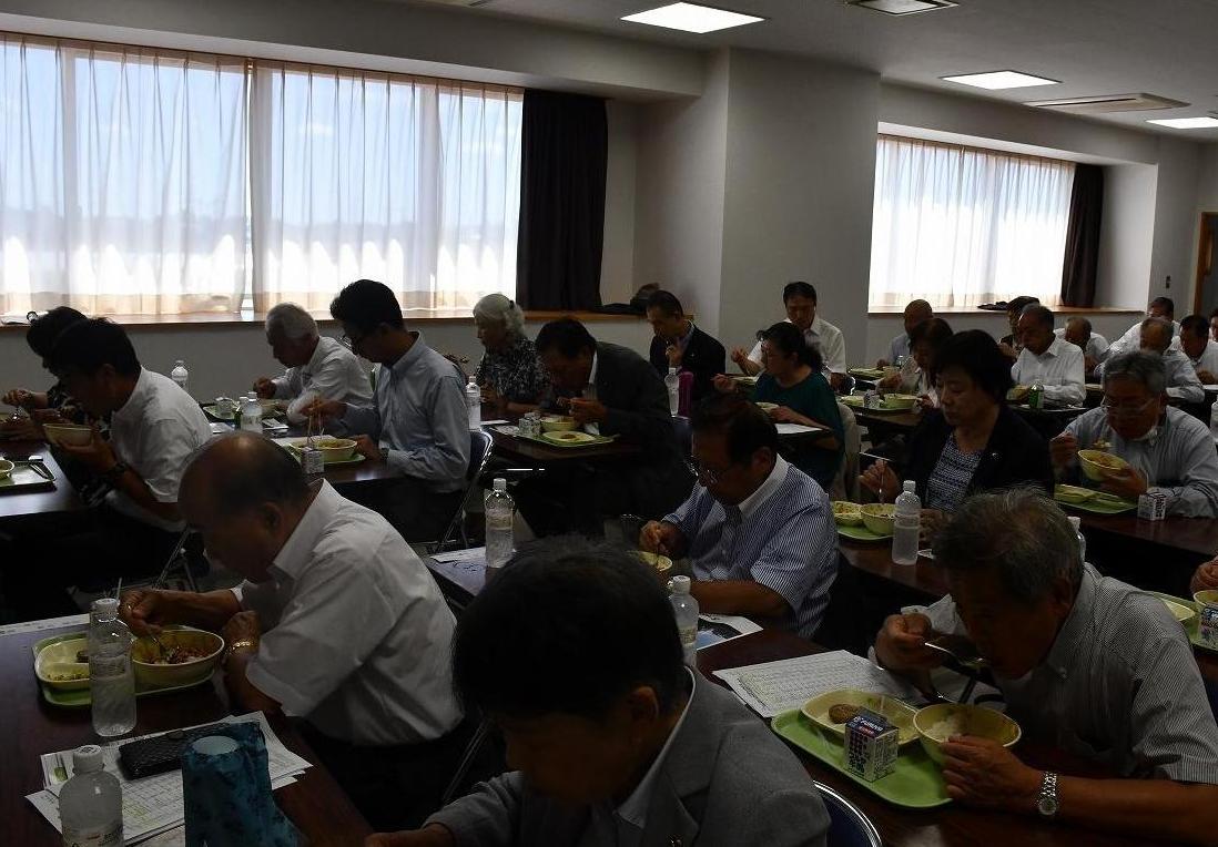 両市町の議員及び関係者が給食を試食している様子