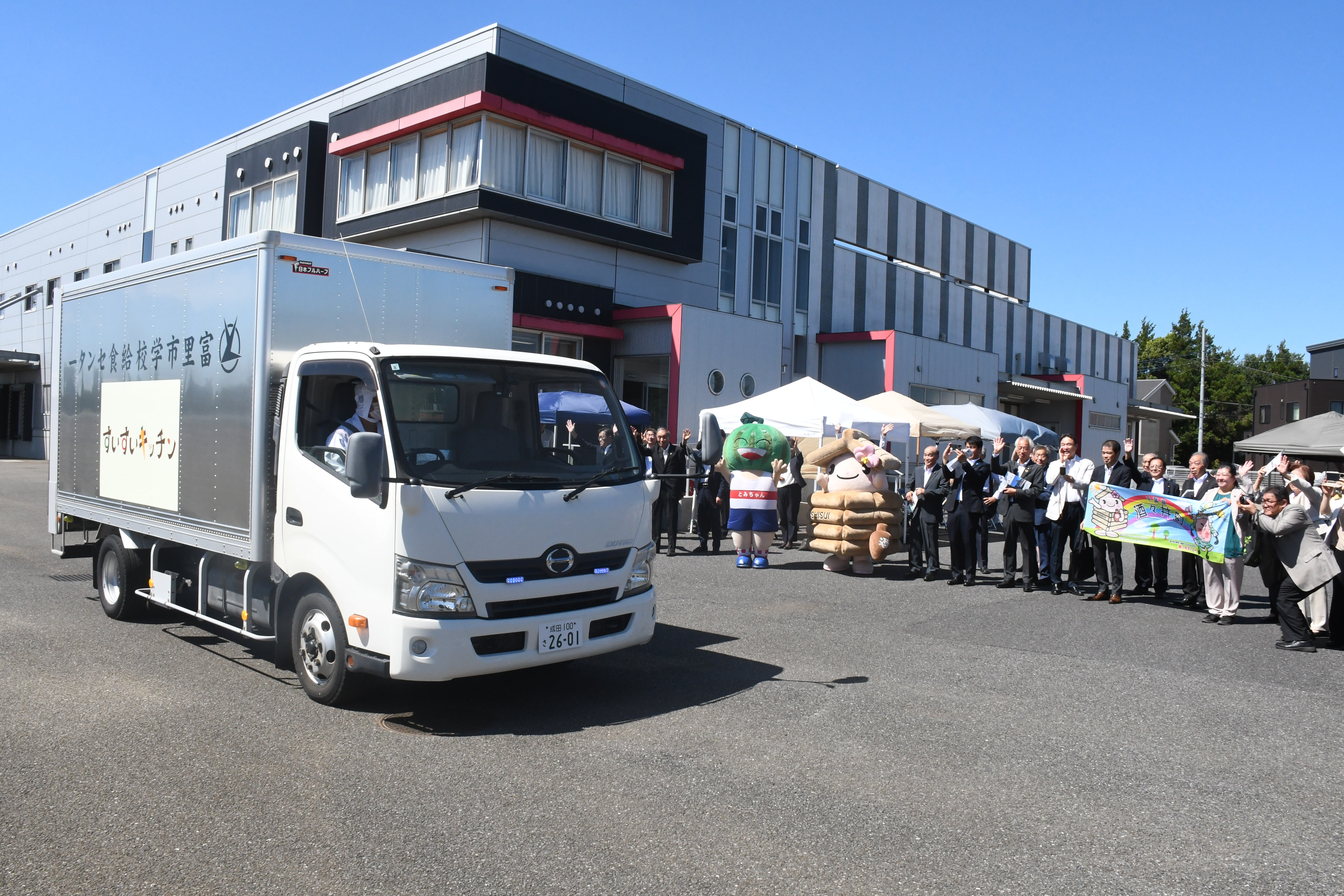 給食を載せたトラックを富里市と酒々井町の関係者が見送る様子