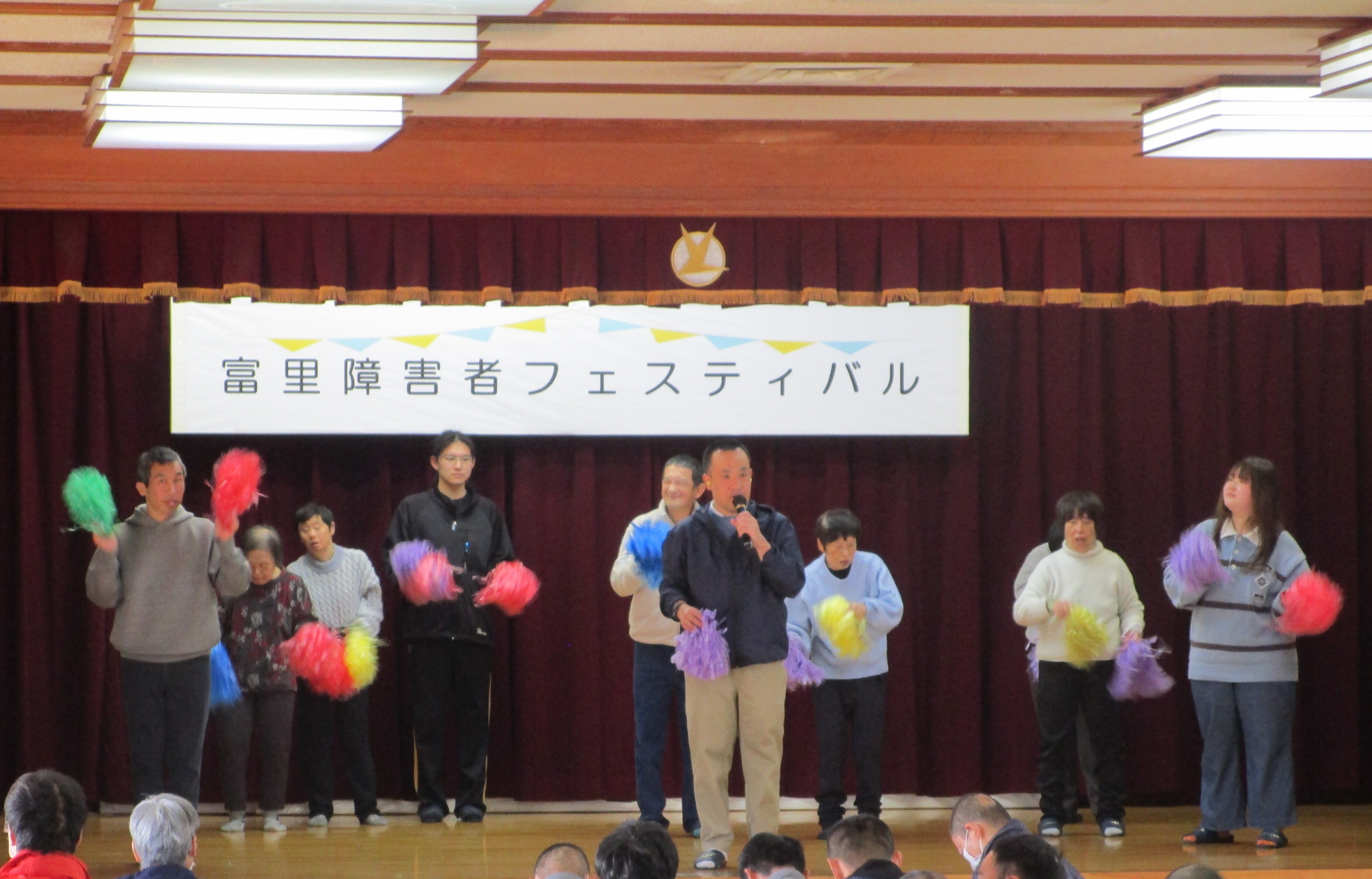 十数人が舞台の上で歌とダンスをしている様子