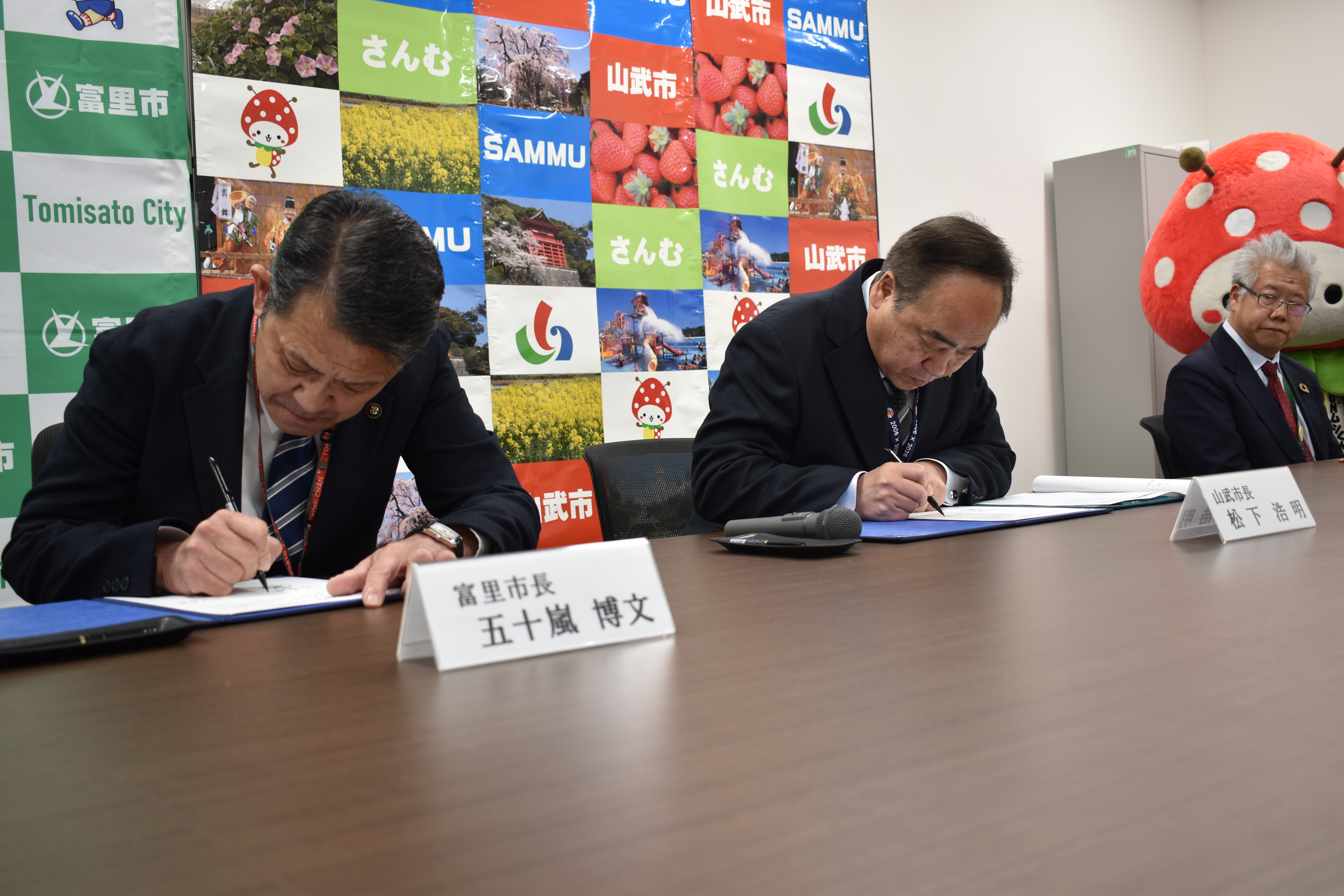 協定書にサインをする両市長